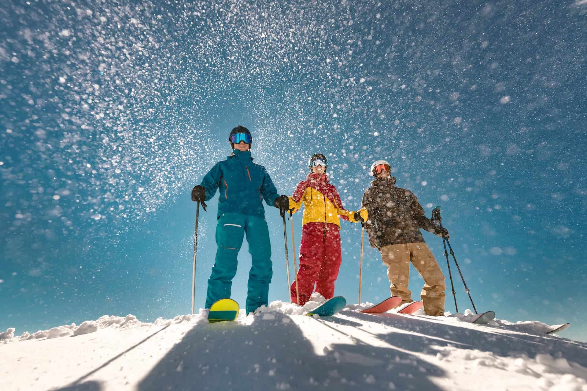 Where To Ski And Snowboard At Whistler Blackcomb By Ability Level. Group Of Three Skiers Stands Against Sun And Snowfall In Whistler.